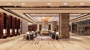 Un hall d’entrée spacieux, doté d’un espace salon central, d’un grand lustre et d’un design moderne.