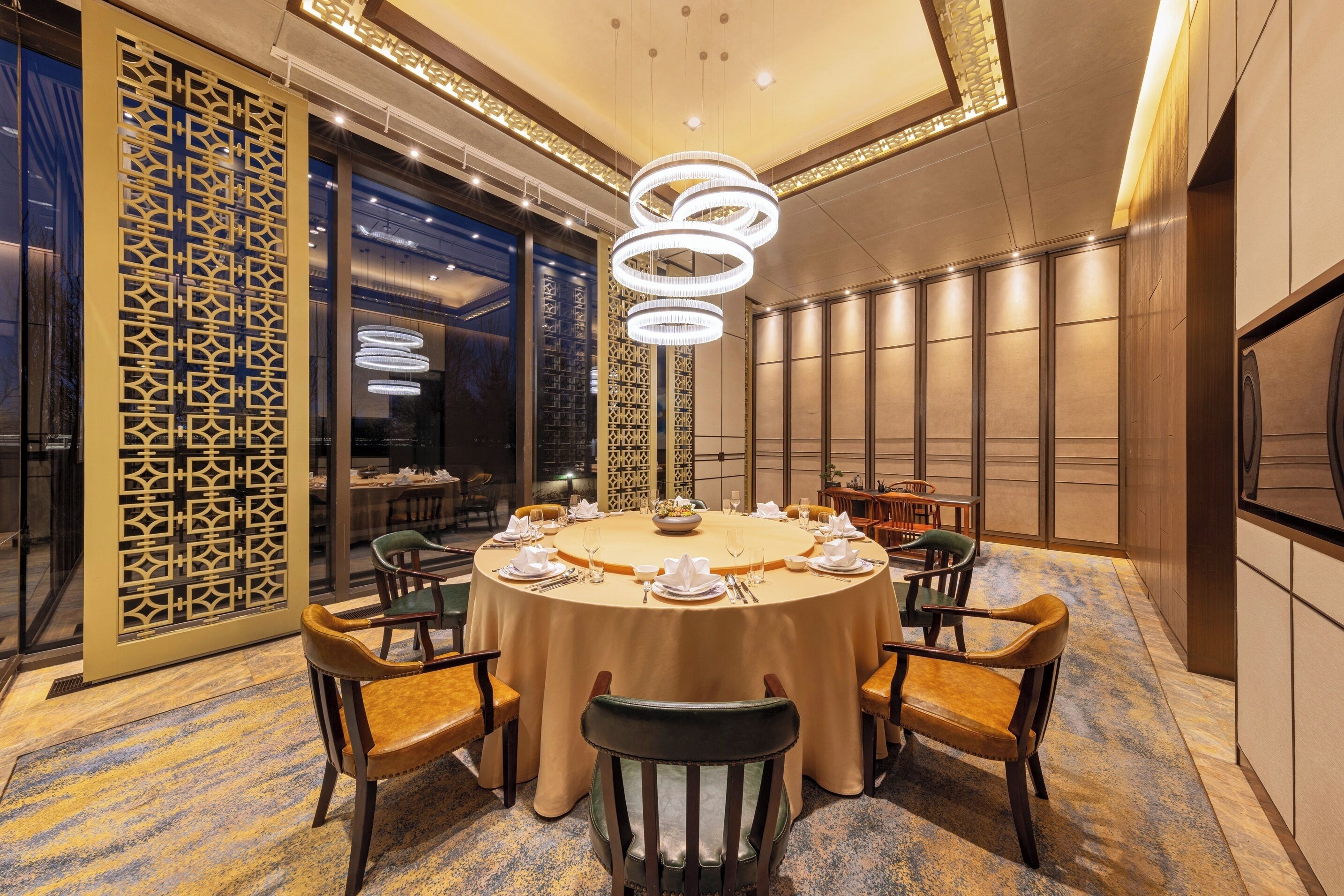 Un tavolo rotondo da pranzo con sedie, una parete decorativa e un lampadario moderno.
