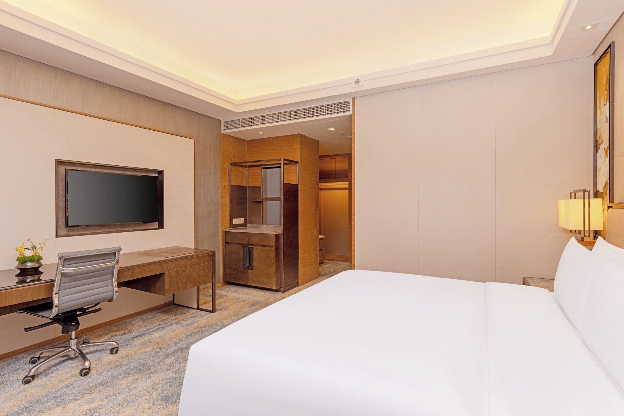 Habitación de hotel con cama, escritorio con silla, televisión, armario y baño.