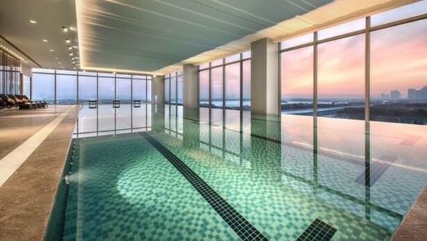 Une piscine intérieure moderne offrant une vue dégagée sur les gratte-ciel de la ville grâce à de grandes fenêtres.