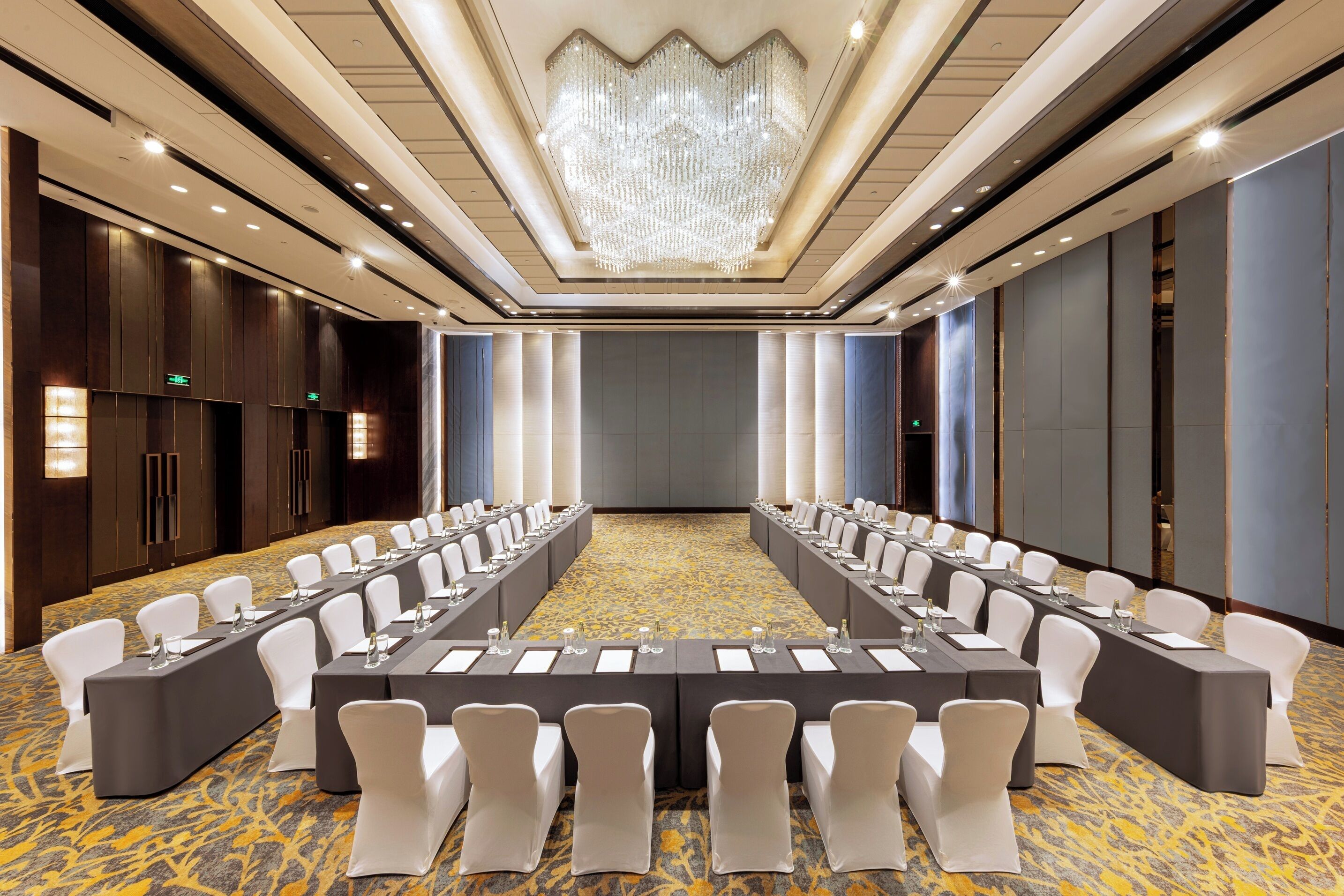 A conference room with a long table, white chairs, and a chandelier.