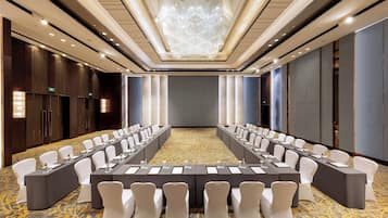 A conference room with a long table, white chairs, and a chandelier.