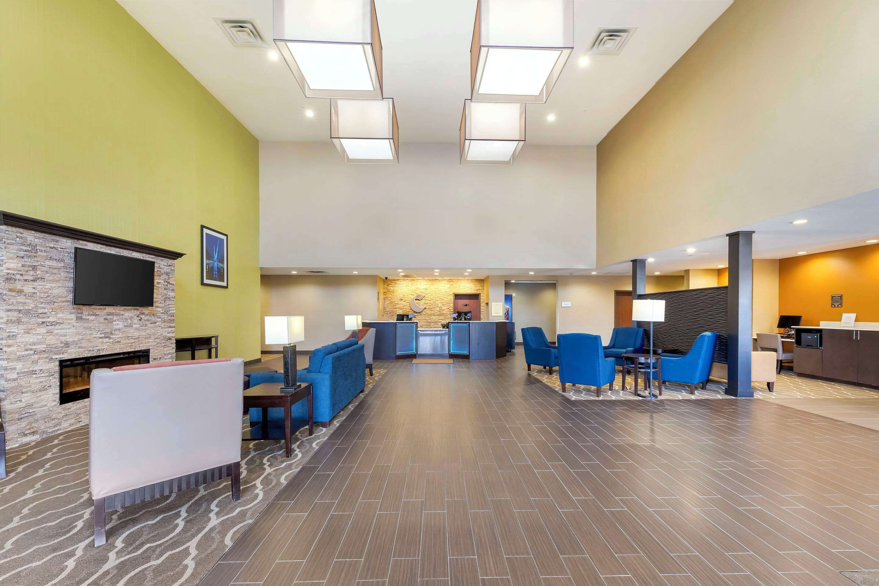 A spacious lobby with a reception desk, blue seating area, and a stone fireplace.