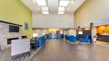 A spacious lobby with a reception desk, blue seating area, and a stone fireplace.