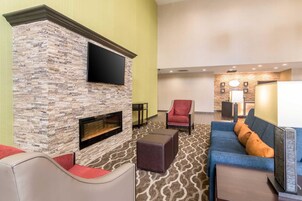 A modern lounge area with a stone fireplace, comfortable seating, a flat-screen TV, and a reception desk.