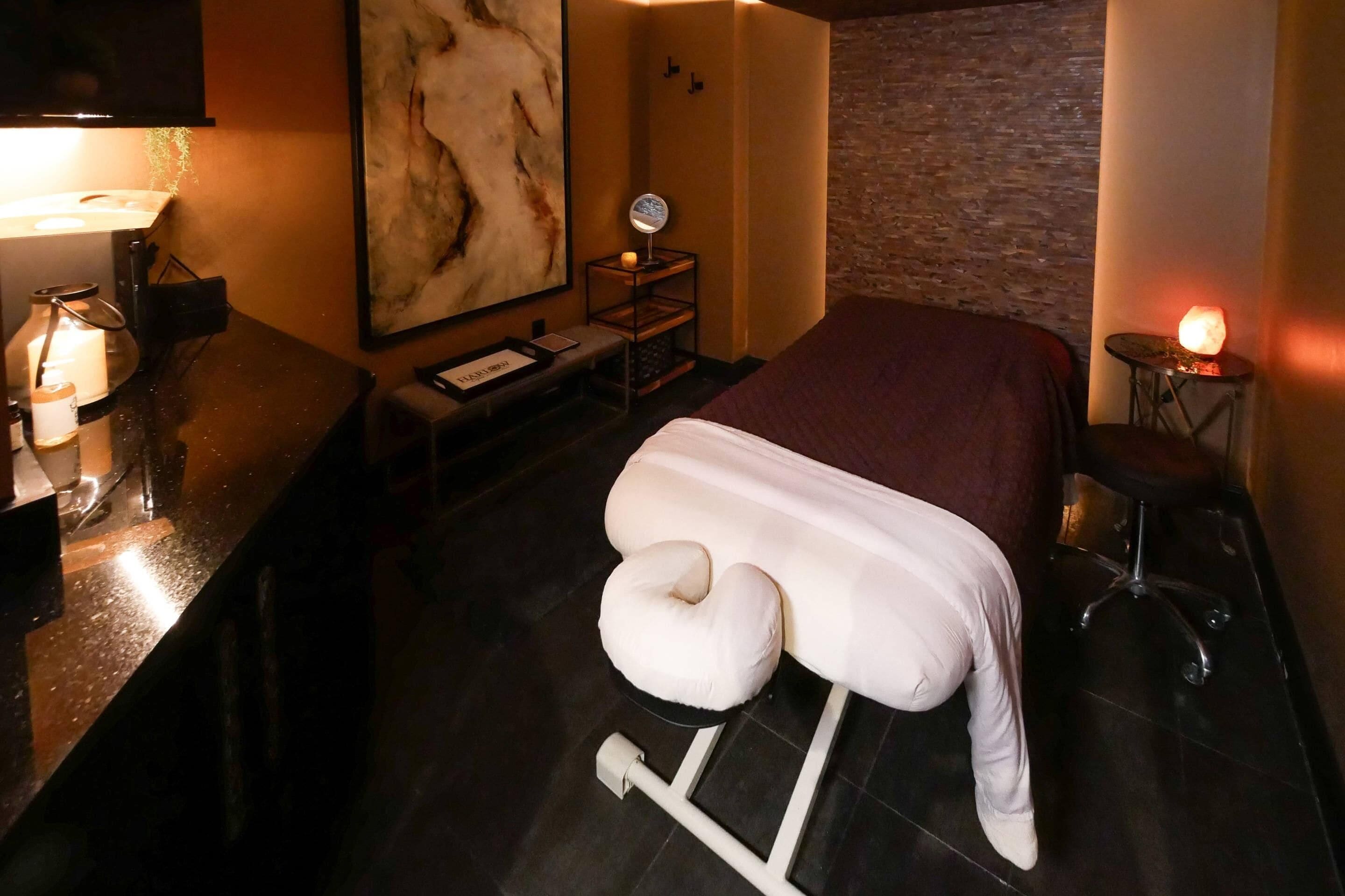 Une chambre d’hôtel avec un lit, une table de chevet, une lampe, une œuvre d’art murale et une petite table avec une bougie.
