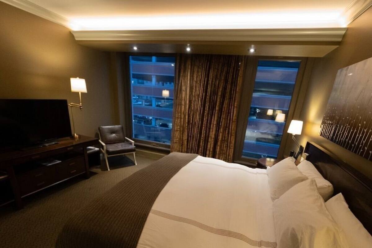Habitación de hotel con una cama grande, televisión, escritorio y vistas a la ciudad.