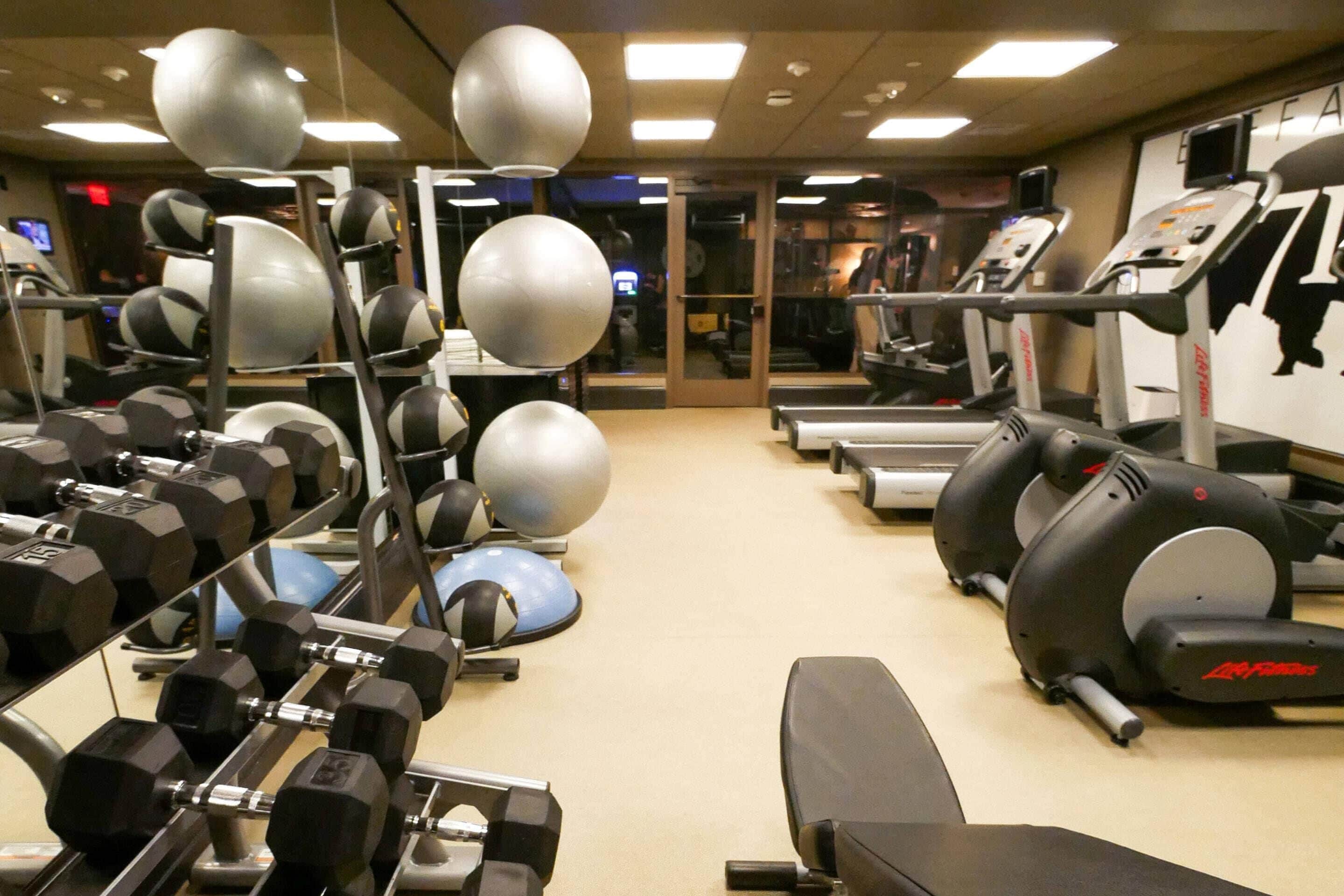 A gym with exercise equipment, treadmills, and dumbbells.