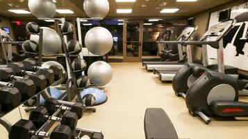 A gym with exercise equipment, treadmills, and dumbbells.