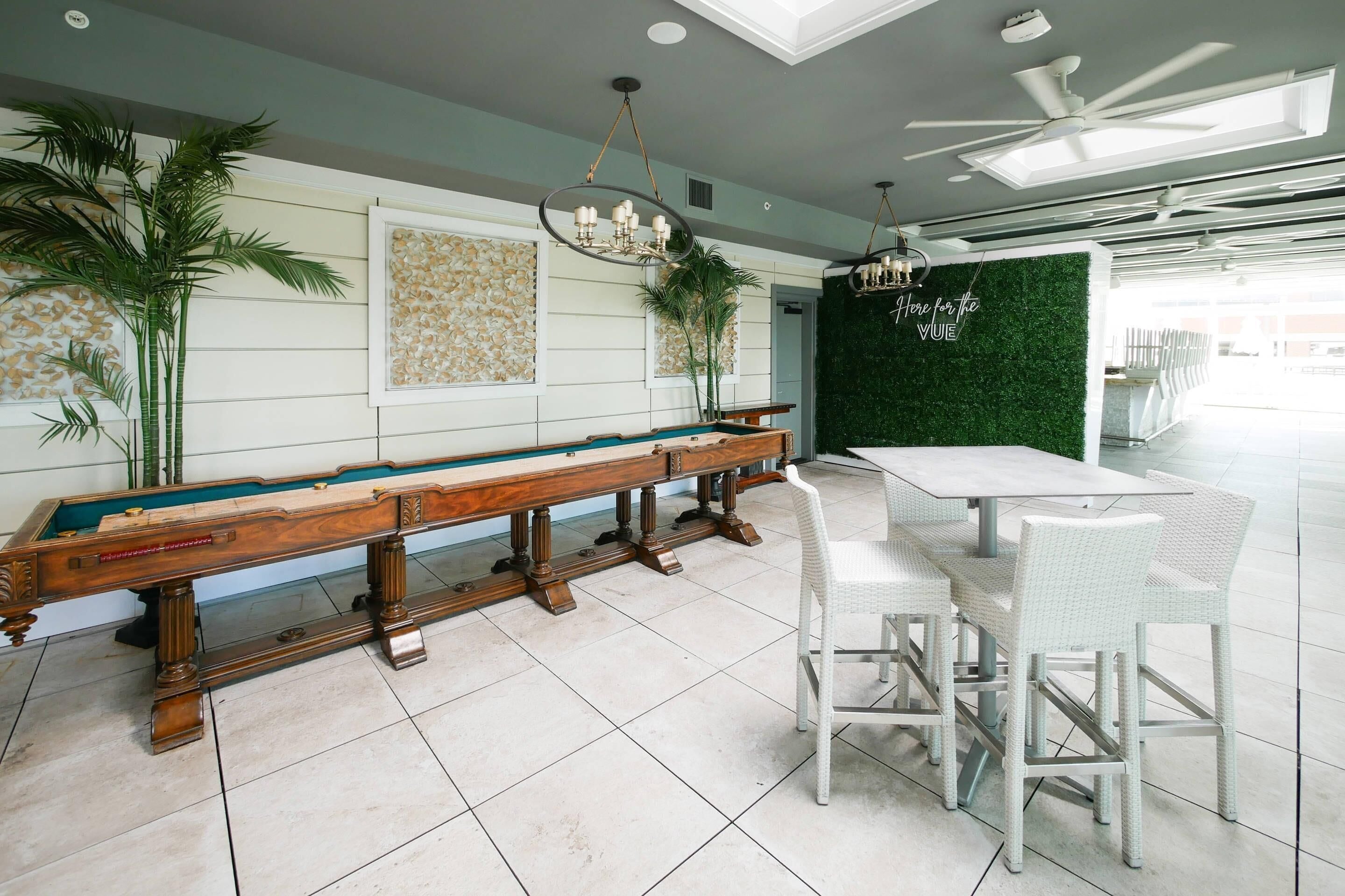 A billiards table, a green wall with a 'Here for the Vibe' sign, and a ceiling fan.