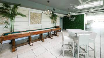 A billiards table, a green wall with a 'Here for the Vibe' sign, and a ceiling fan.