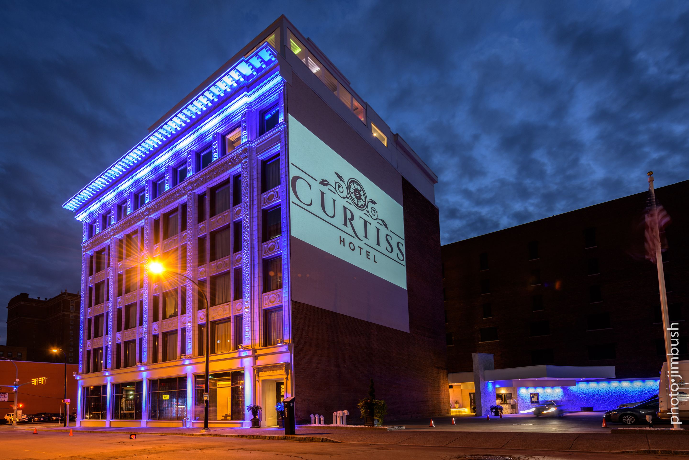 A hotel with a large illuminated sign, a classic architectural design, and a well-lit entrance.