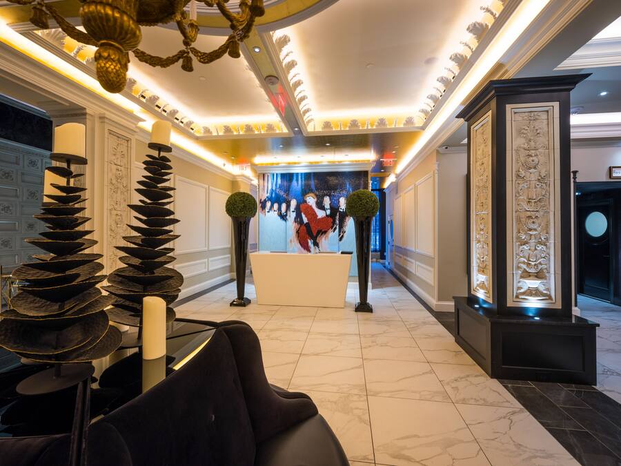 A lobby with a reception desk, a chandelier, and a decorative wall with a painting.