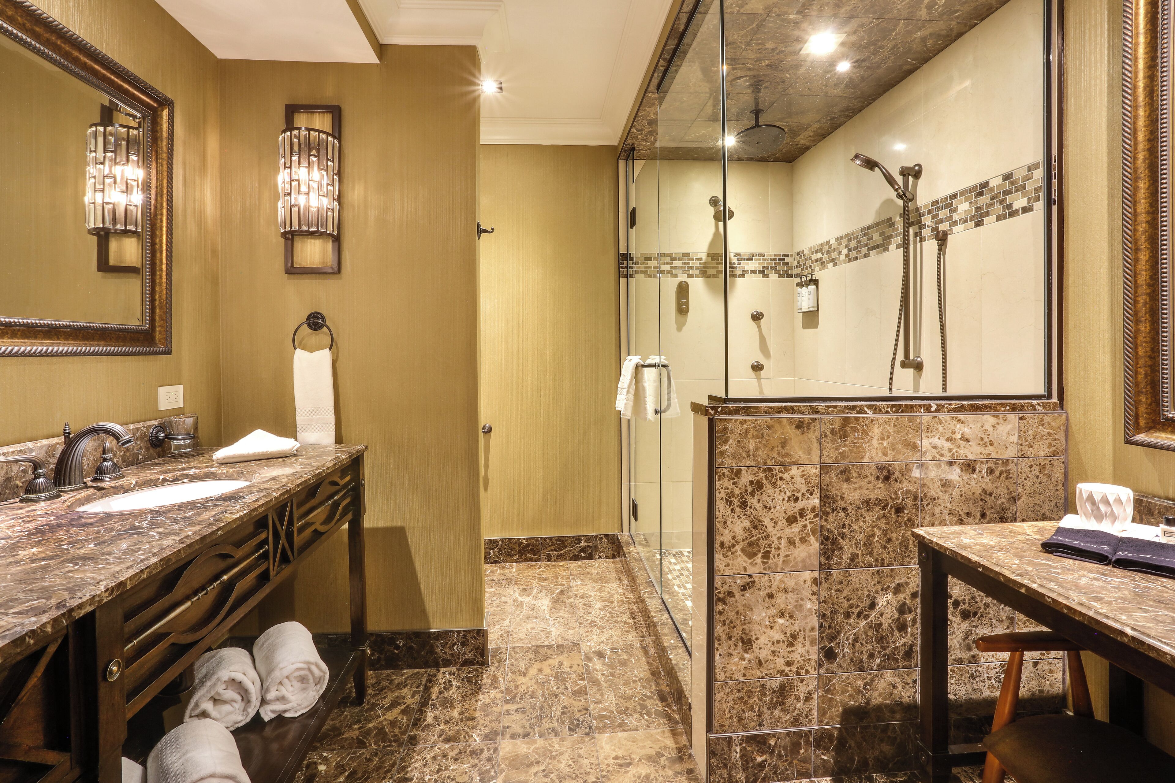 Une salle de bain avec un lavabo en marbre, une douche en verre et un meuble-lavabo avec des serviettes.