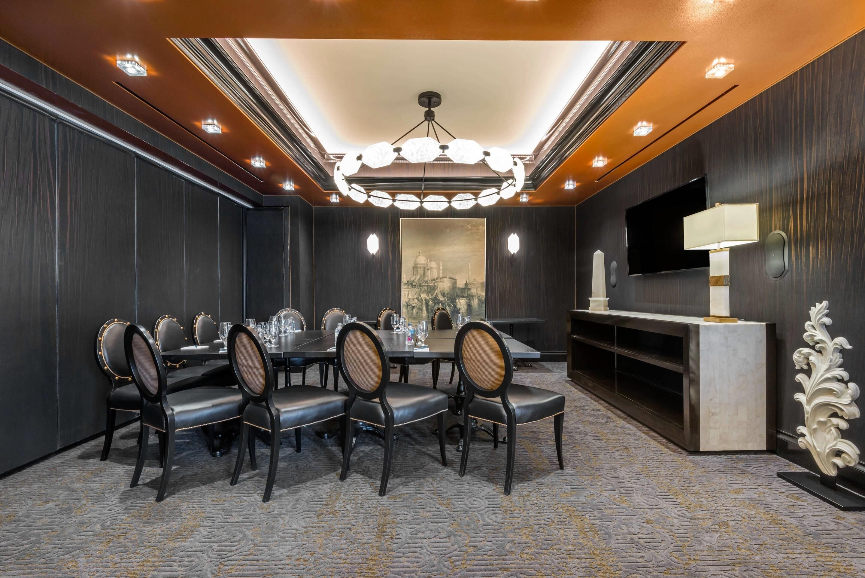 A conference room with a round table, chairs, and a television on a stand.
