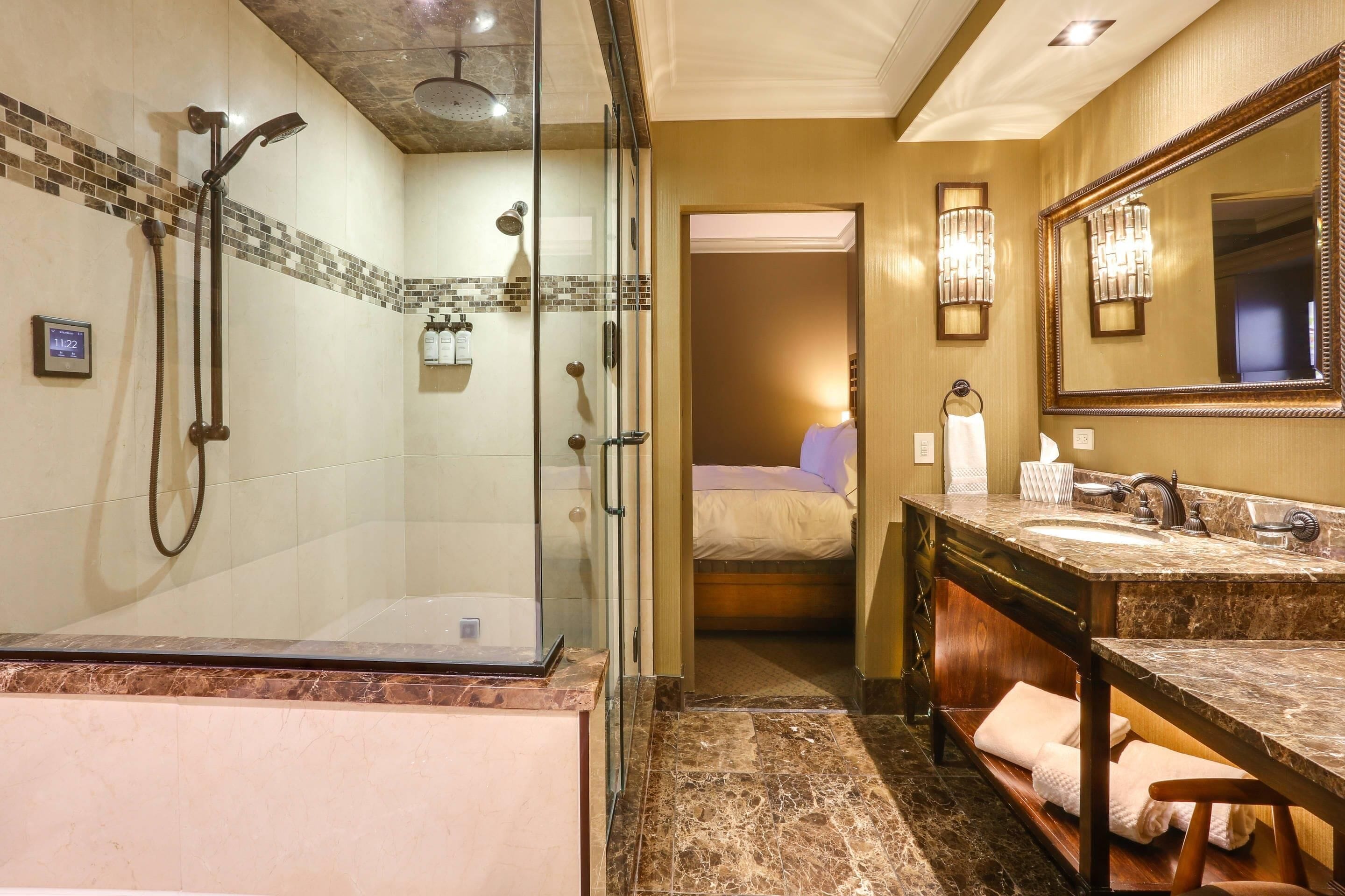 A hotel bathroom with a glass-enclosed shower, a marble sink, and a large mirror.