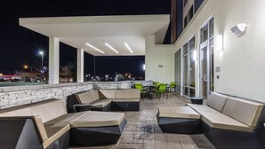 An outdoor patio area with seating and tables, a stone wall, and a view of the city at night. - SpringHill Suites by Marriott Columbia (Columbia)