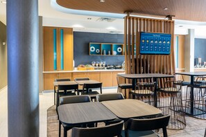A modern restaurant with tables and chairs, a kitchen area, and a 7-day weather forecast display. - SpringHill Suites by Marriott Columbia (Columbia)