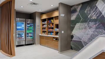 A modern lobby with vending machines, a snack bar, and a staircase.