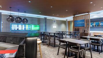 Un restaurante moderno con diversas opciones de asientos, como cabinas y mesas, un amplio menú digital y techo de madera.