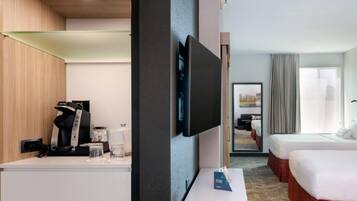 Hotelkamer met een flatscreen-tv, een koffiezetapparaat, een nachtkastje, twee bedden en uitzicht op de stad.