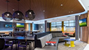 A modern lounge area with a large sofa, dining tables, and hanging pendant lights. - SpringHill Suites by Marriott Columbia (Columbia)