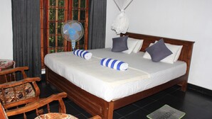 A neatly made bed with a striped towel, a bedside fan, and a wooden headboard. - Kandy Shady Trees Villa (Kandy)