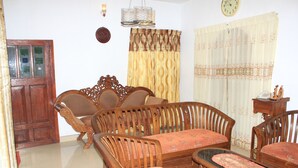 A traditional living room with a sofa set, wooden chairs, a small table, and a clock on the wall. - Kandy Shady Trees Villa (Kandy)
