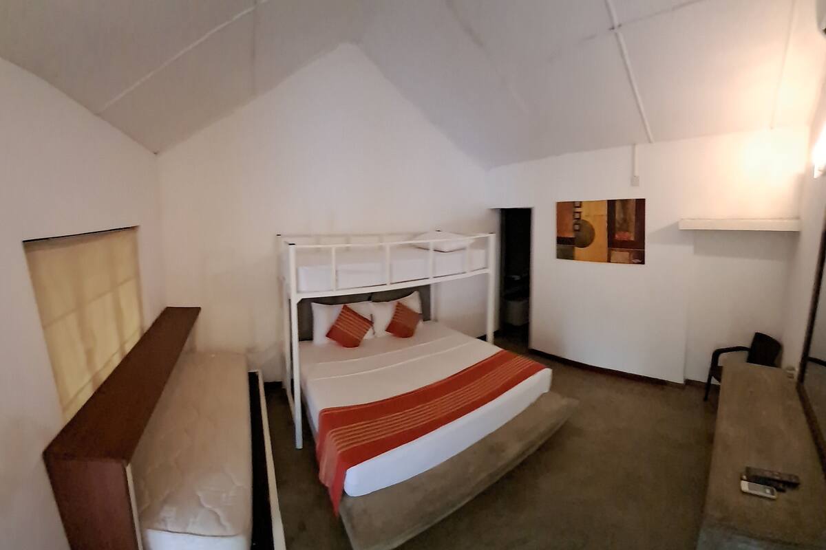Une petite pièce, de taille modeste, comprenant un lit superposé, un bureau et une chaise.