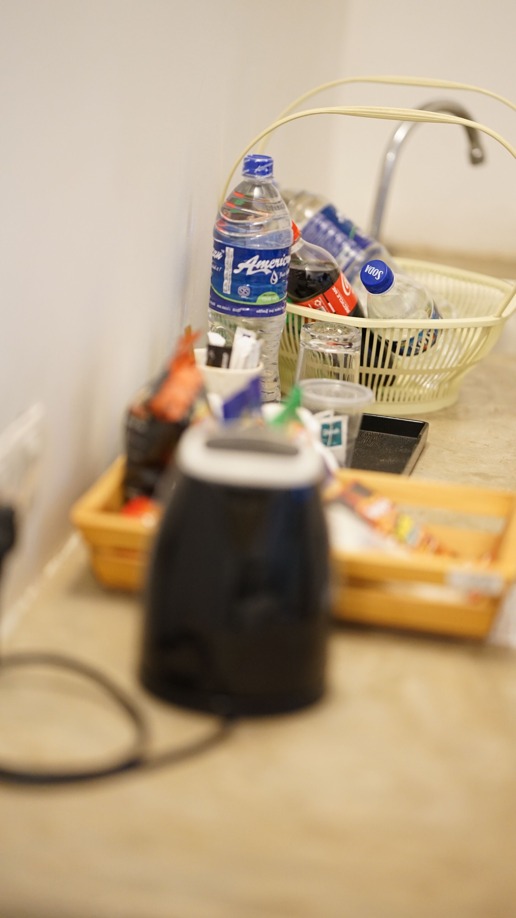 Eine Küchenarbeitsplatte mit Kaffeemaschine, einer Wasserflasche, einem Korb und verschiedenen Küchenutensilien.