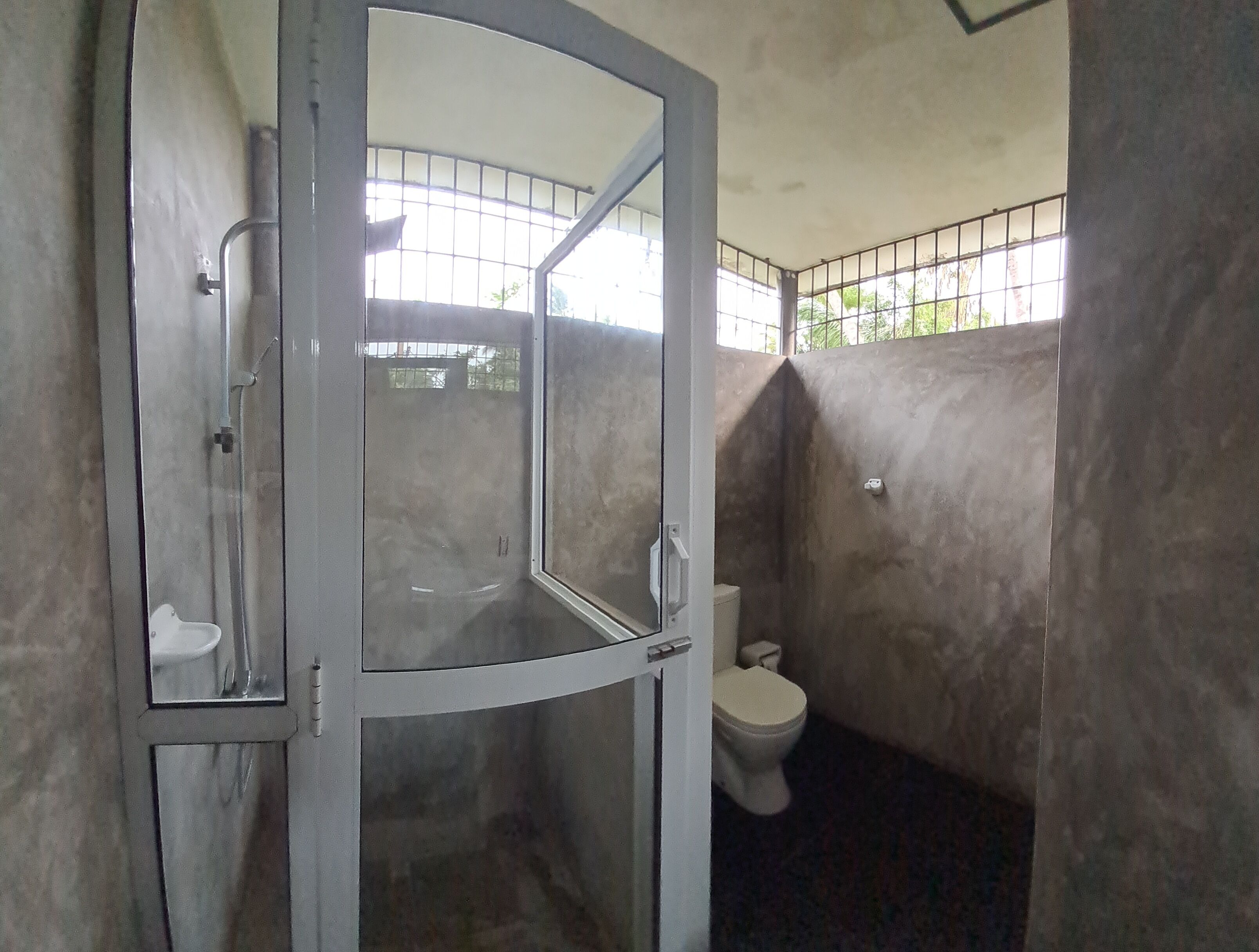 Un baño con ducha, inodoro y espejo.