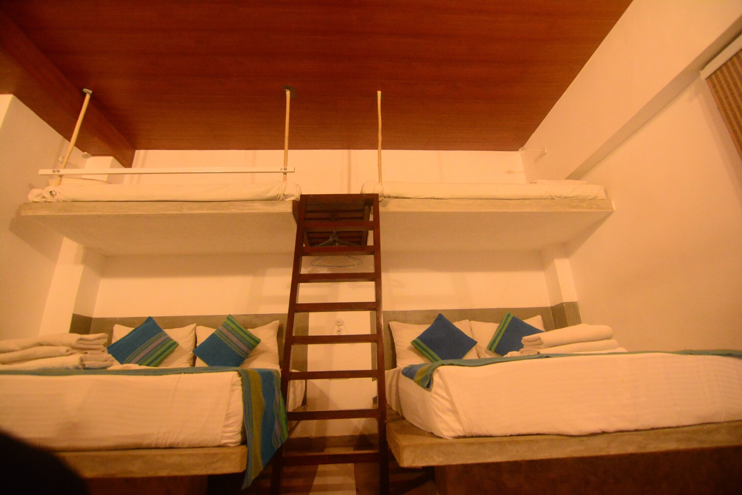 A room with two bunk beds, a wooden ladder, and a small table.