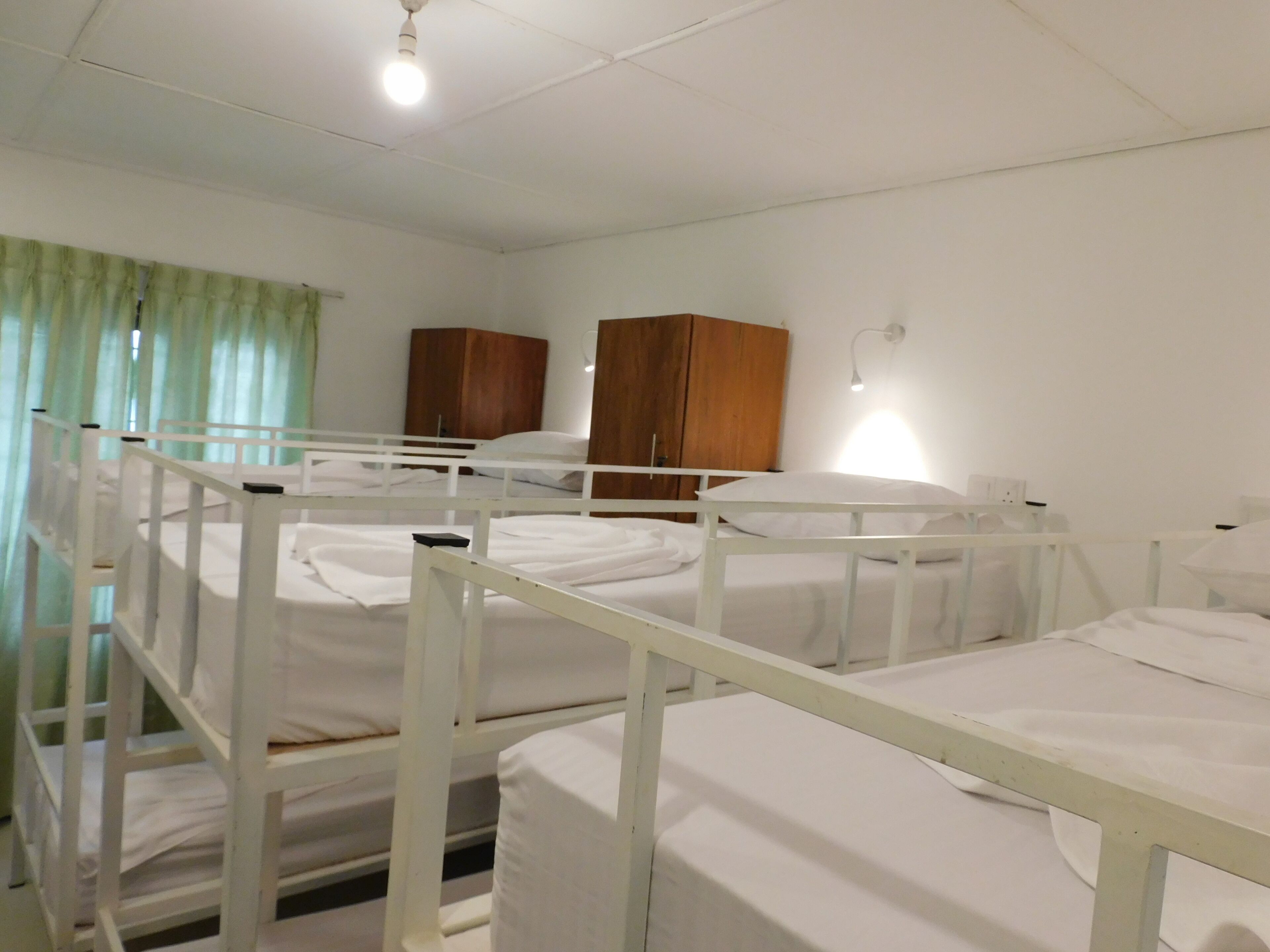 Une chambre d’hôpital avec des lits superposés, des armoires en bois et une seule lampe de chevet.