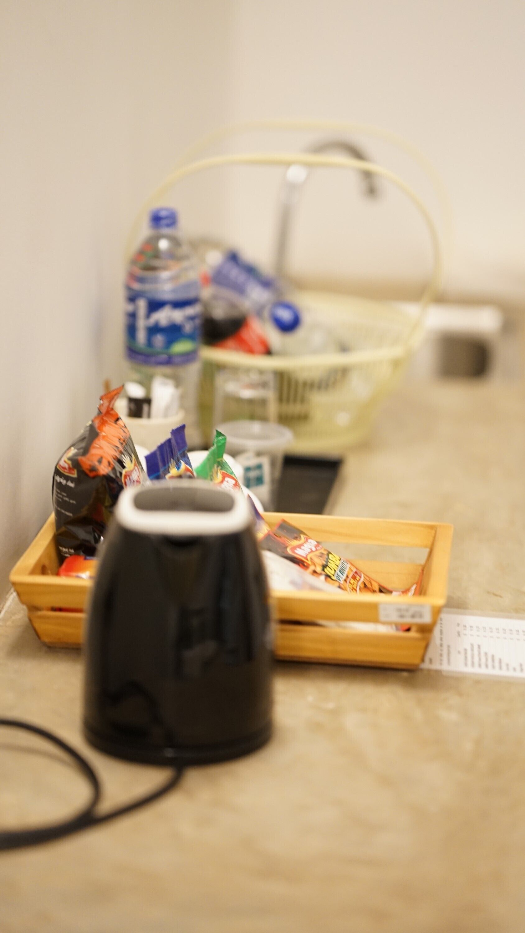 Una kitchenette con cafetera, una cesta de aperitivos, una botella de agua y una caja de pañuelos.