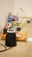 Una kitchenette con cafetera, una cesta de aperitivos, una botella de agua y una caja de pañuelos.