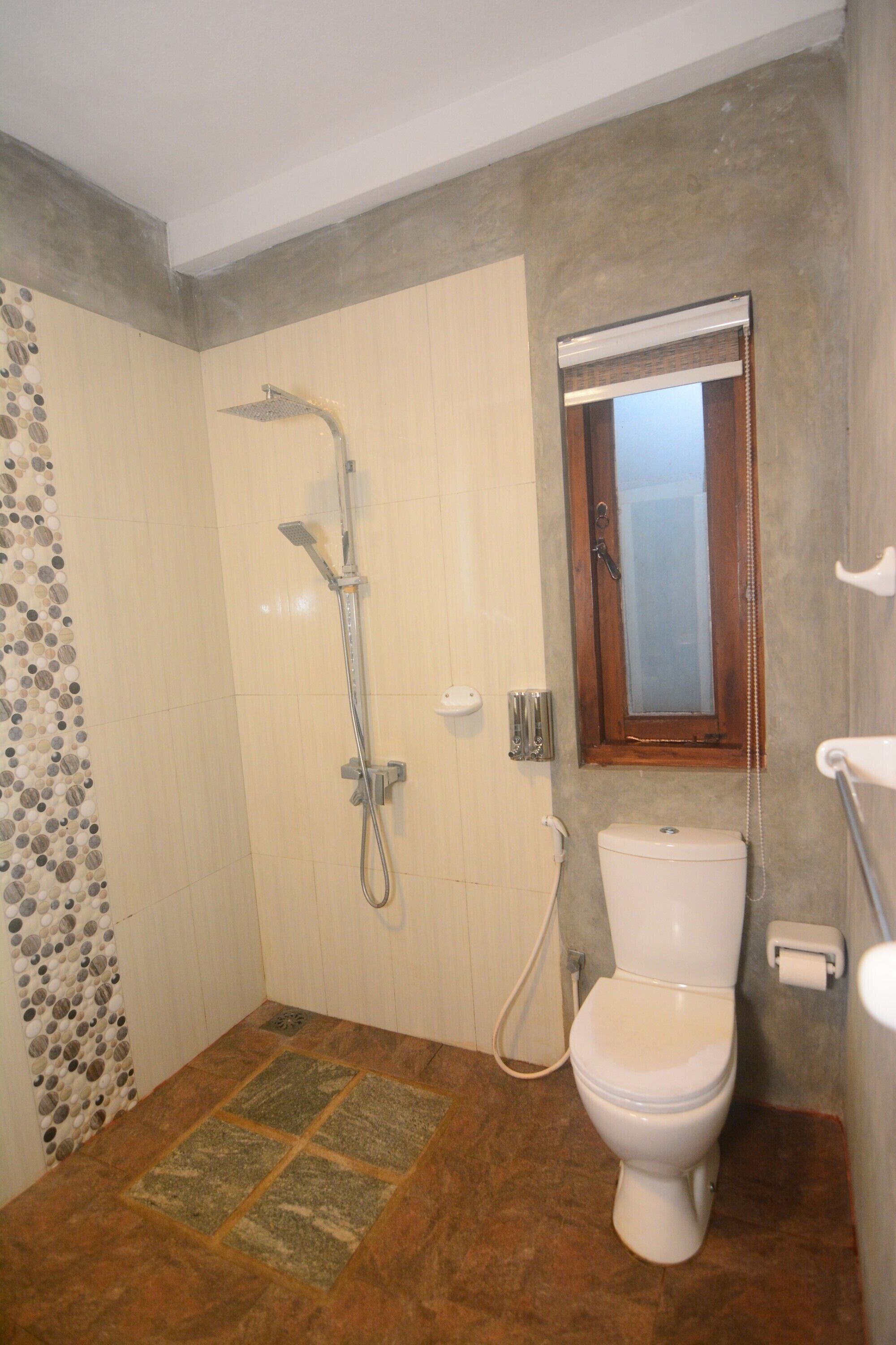 A bathroom with a shower, toilet, and a window.