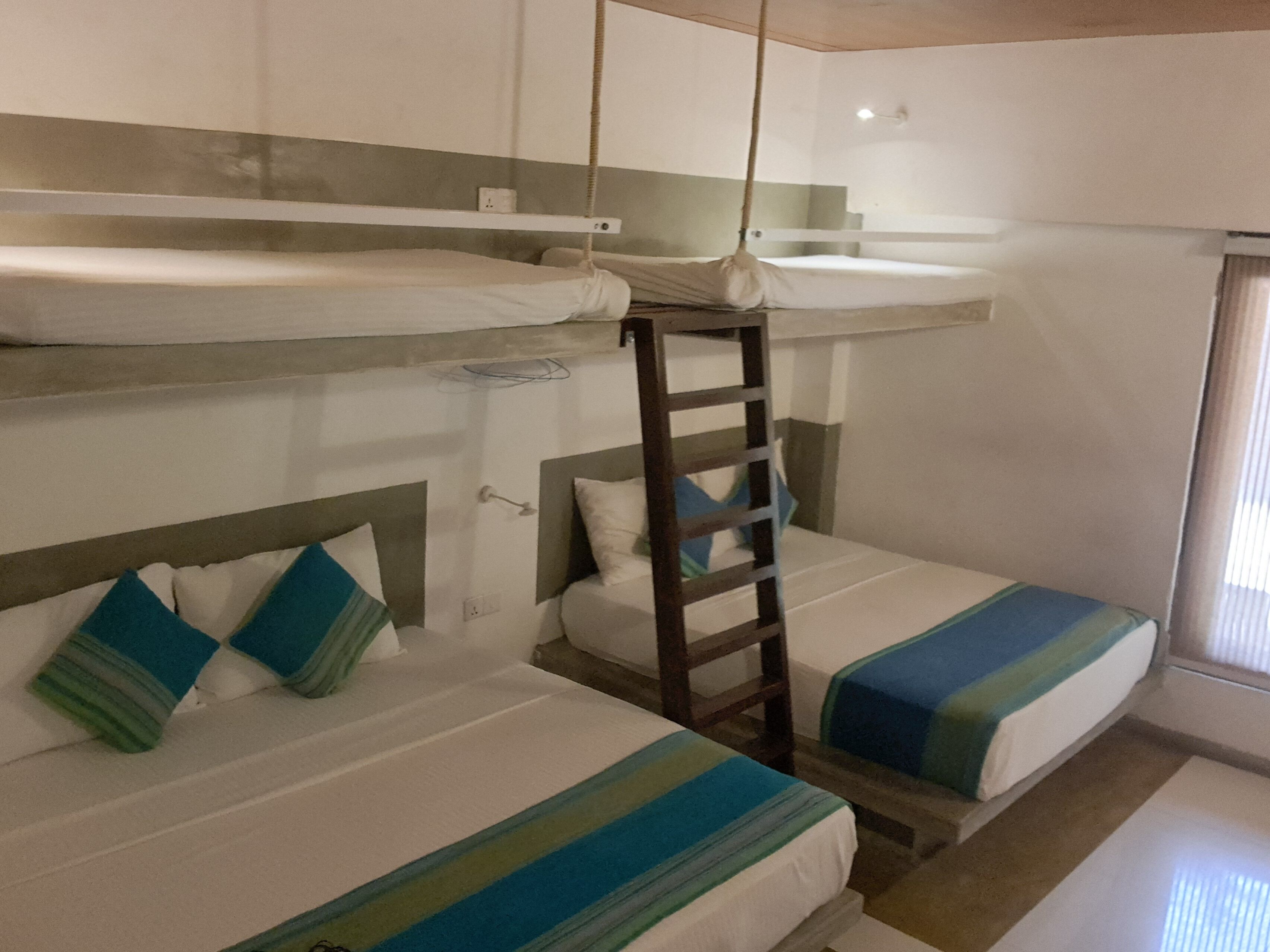 A bunk bed room with a ladder, a window, and a wall socket.