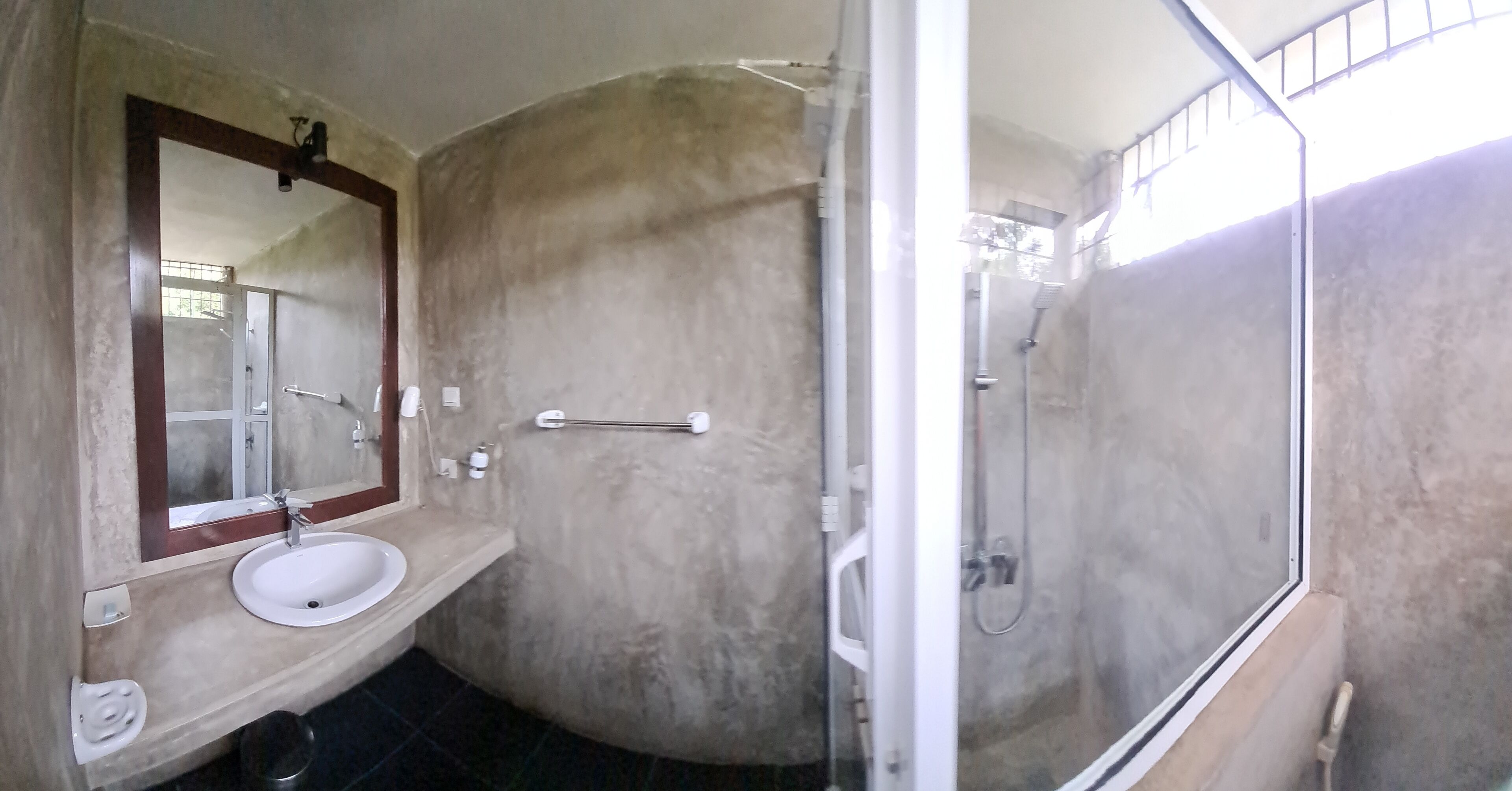 A bathroom with a sink, mirror, towel rack, and a glass-enclosed shower area.
