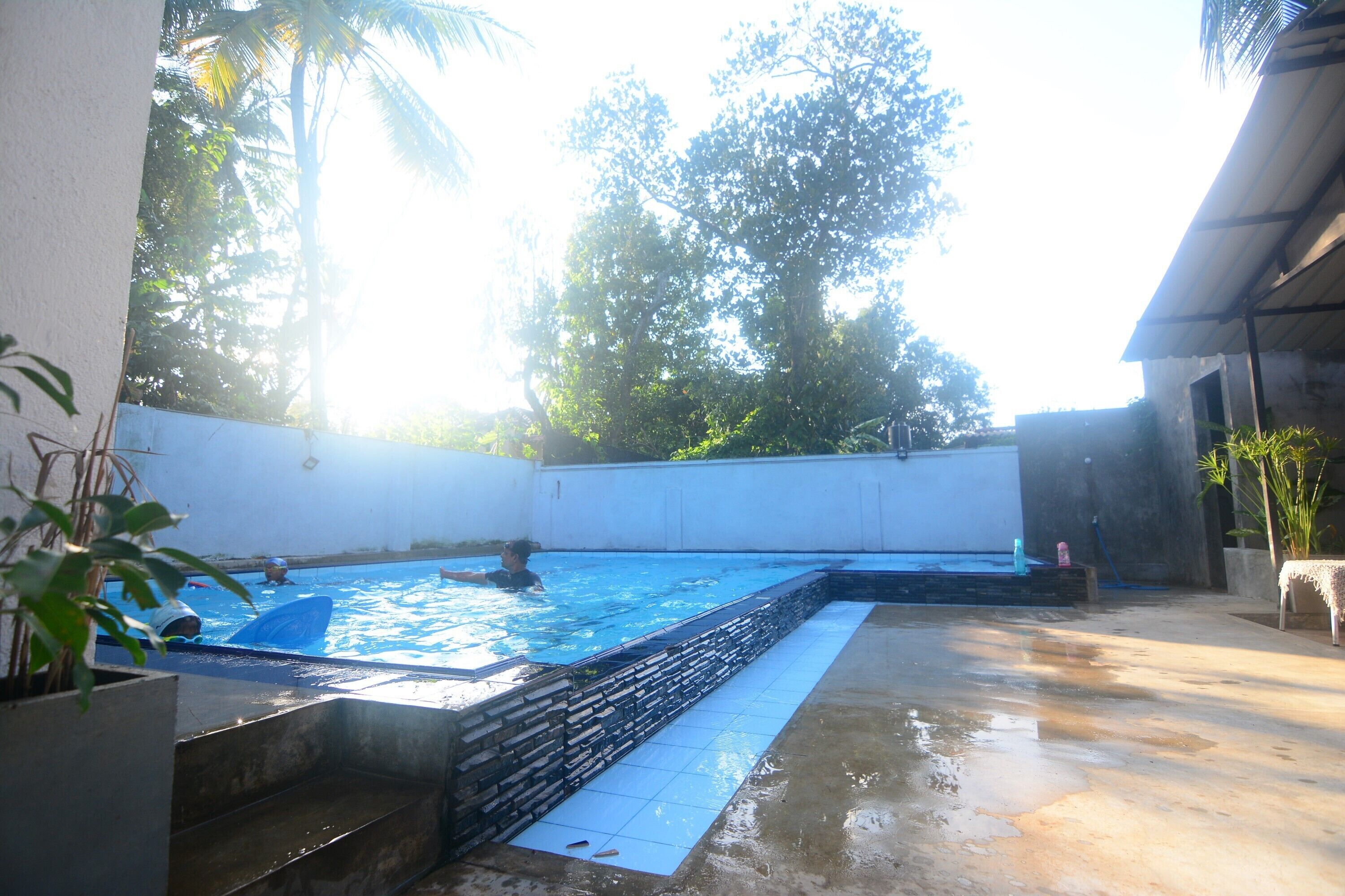 Una piscina con borde de piedra y zona de solárium con baldosas.