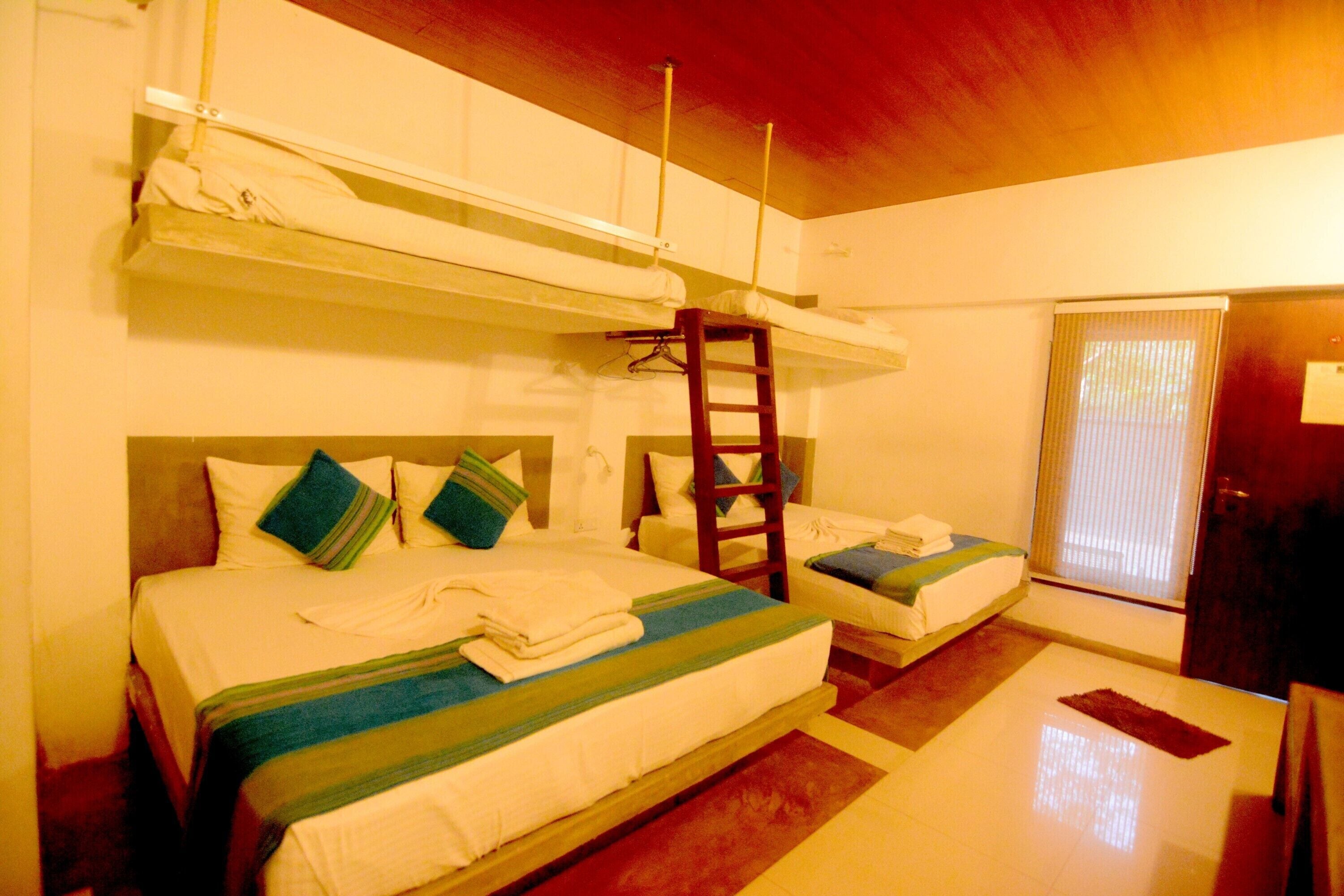 A room with bunk beds, a ladder, a small table, and a door.