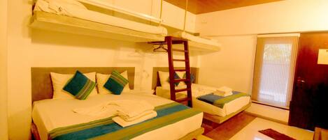 A room with bunk beds, a ladder, a small table, and a door.