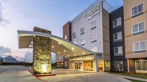A hotel entrance with a stone pillar, a covered walkway, and multiple floors with windows.