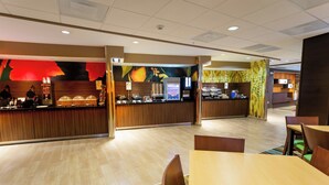 A modern hotel lobby with a reception area, a buffet, and seating arrangements.