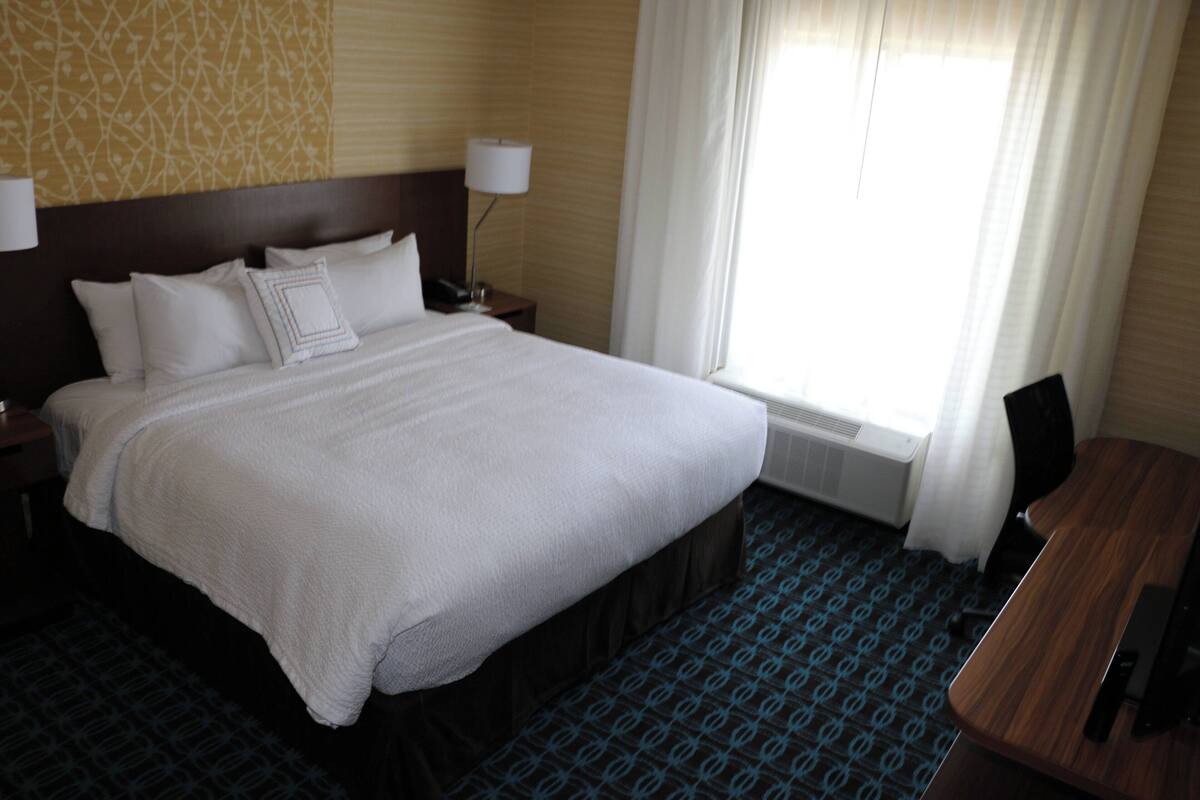 A hotel room with a large bed, a desk, and a chair.