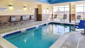An indoor swimming pool with clear water, a lifeguard duty sign, and no diving sign.