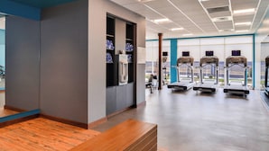A modern gym with exercise equipment, a reception area, and large windows offering a view.