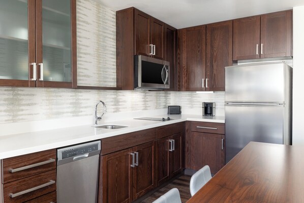 A modern kitchen with wooden cabinets, stainless steel appliances, and a white countertop. - Residence Inn by Marriott Denver Central Park (Denver)