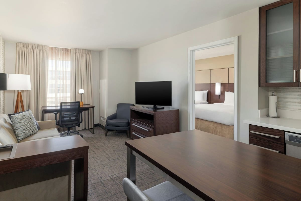 A hotel room with a bed, a desk, a chair, a television, and a cabinet.