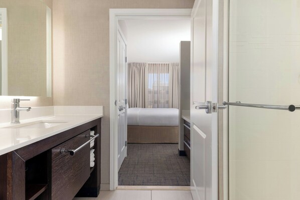 A hotel bathroom with a large mirror, a sink, and a shower area. - Residence Inn by Marriott Denver Central Park (Denver)