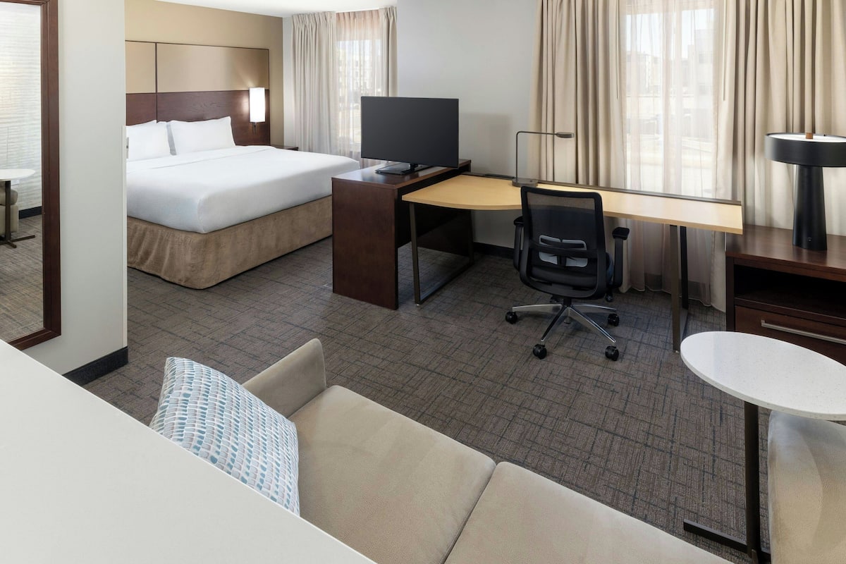 A hotel room with a bed, desk, chair, and a small table.
